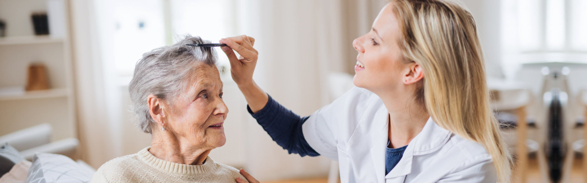 health visitor combing hair of senior woman at home