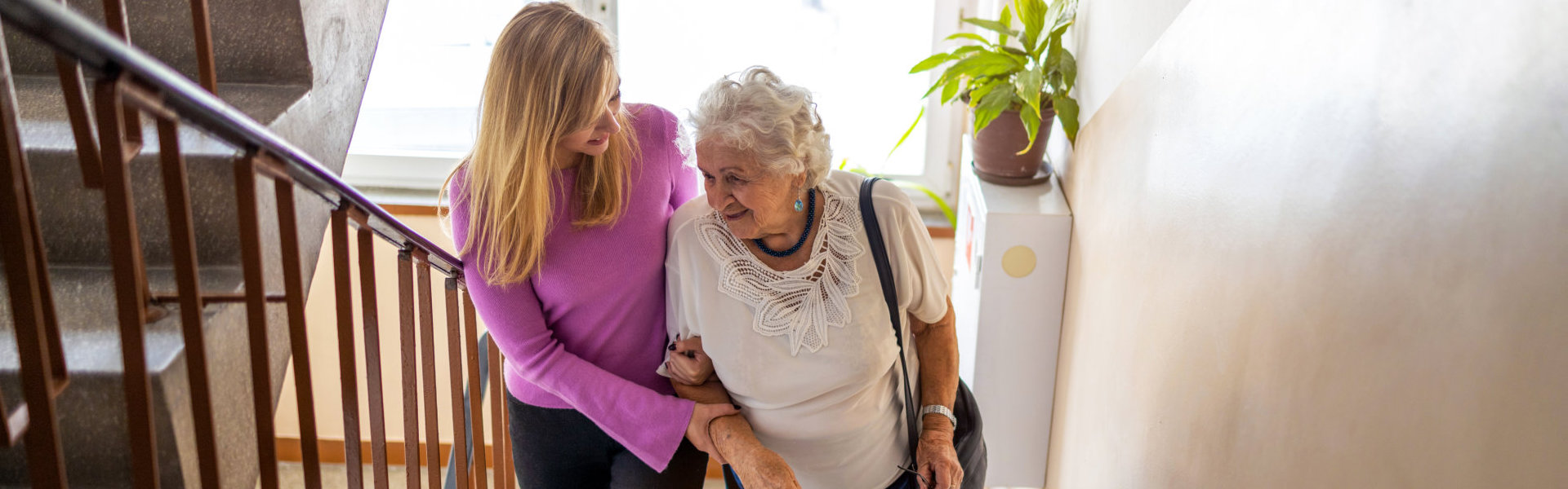 Caregiver helping senior woman climb staircase