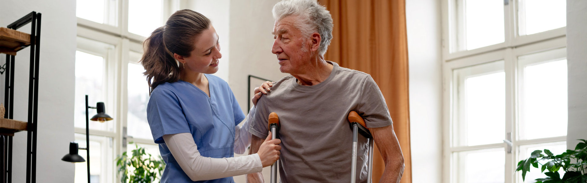 Young nurse helping senior man with walking